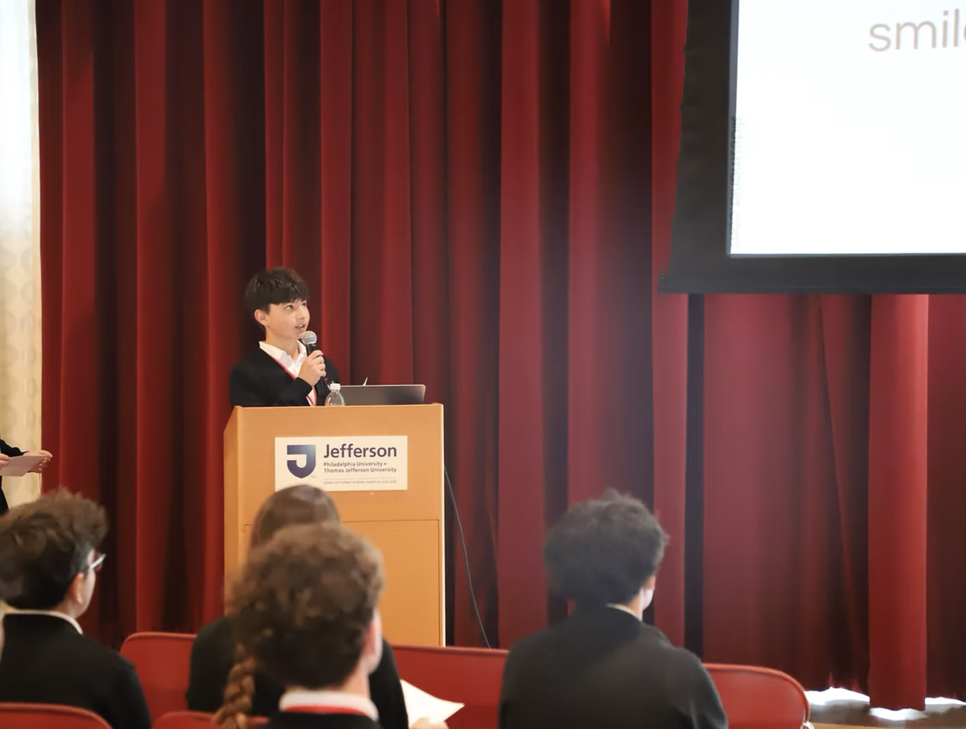 Student stands at podium at entrepreneurship presentation.